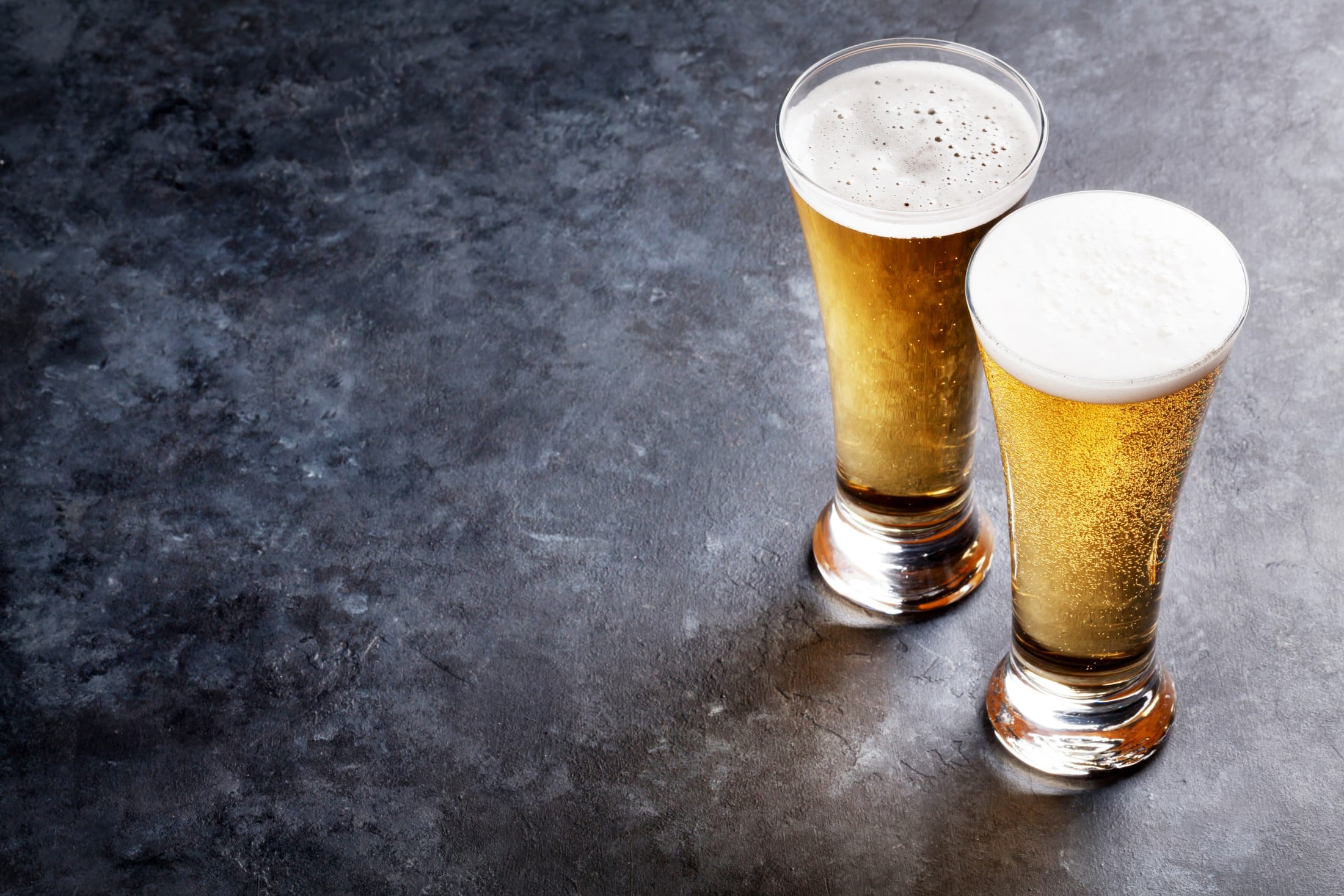 Two glasses of beer on dark stone